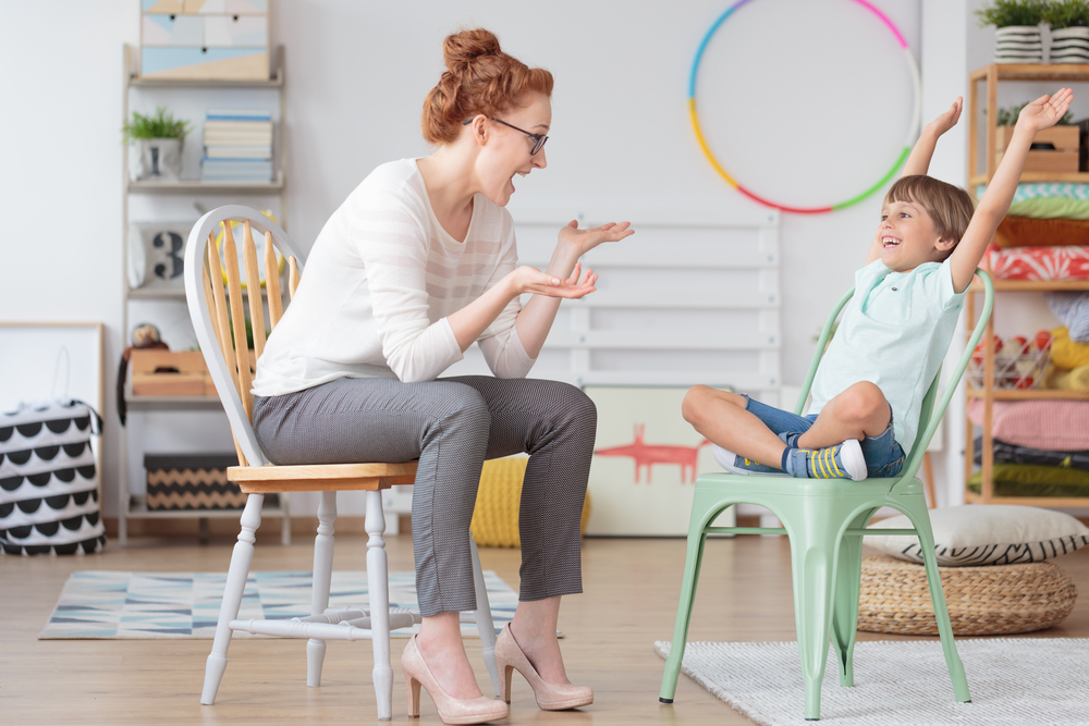 Teacher with developmental delay child sitting in chairs laughing with each other